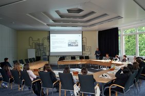 Schüler:innen sitzen im Sitzungssaal des Landratsamtes, der Landrat hält einen Vortrag.